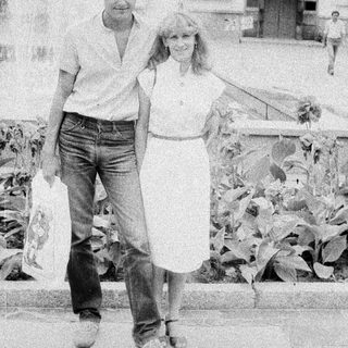 Here's a brief summary of the image: Couple walking outdoors, appearing relaxed and casual.