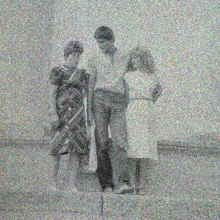 Three children standing on steps, appearing to be outdoors.