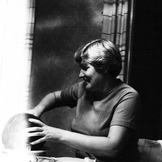 Woman seated, appears to be holding a bowl or globe.