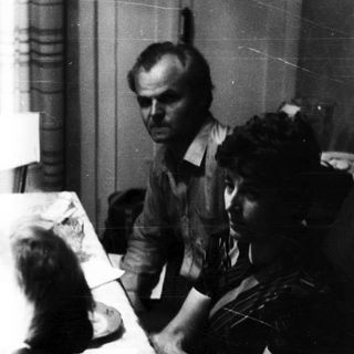Man and two women seated at a table indoors.