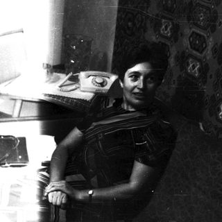Here's a brief summary: Woman in traditional dress seated near a vintage telephone.