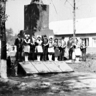 Group poses near a statue, likely for a commemorative event.