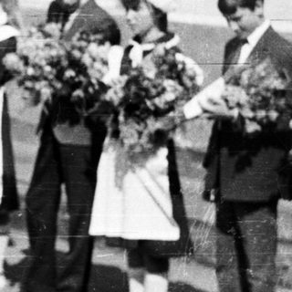 Group of children in formal wear stand outside a building.