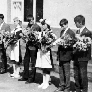 Group of children in formal wear stand outside a building.