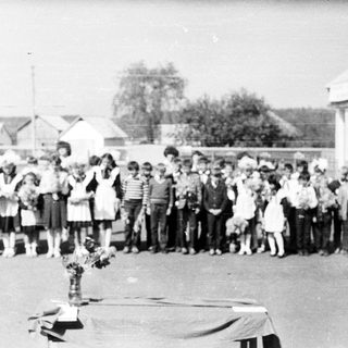 Group of children standing outside a building in a line.