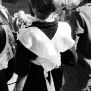 Children in aprons observe an event outdoors.