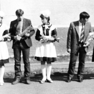 Group of people in vintage clothing stand outdoors.