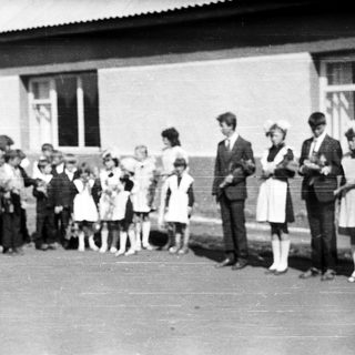 Group of children and adults stand outside a building.