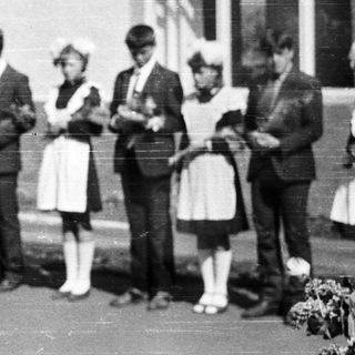 Group of children and adults stand outside a building.