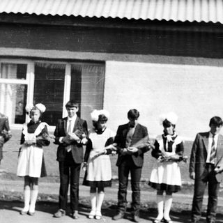 Group of people in vintage attire stand outside a building.
