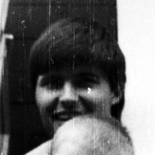 Here's a brief summary of the image: Person and baby peering out of a window.