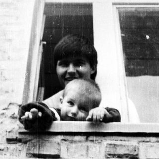 Here's a brief summary of the image: Person and baby peering out of a window.