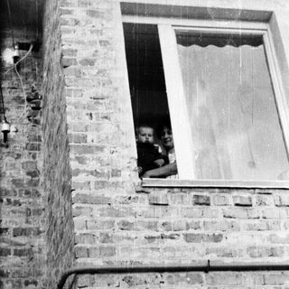 Here's a brief summary of the image: Woman holding a baby, visible in a window.