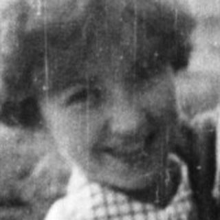 Woman holding a young child near a picnic table.