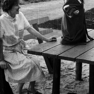 Woman and child stand outdoors during a rain shower.