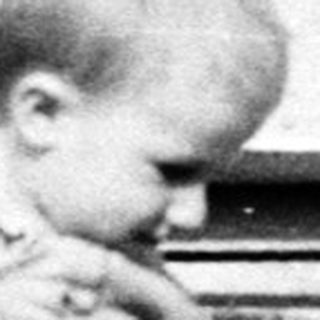 Man holds child up in front of a brick building.