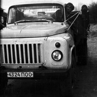 Man driving a vintage truck on a rural road.