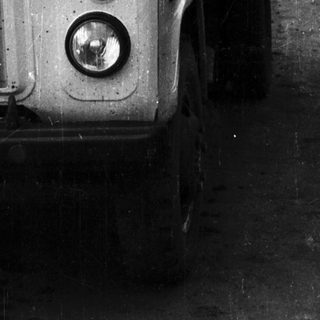 Man driving a vintage truck on a rural road.