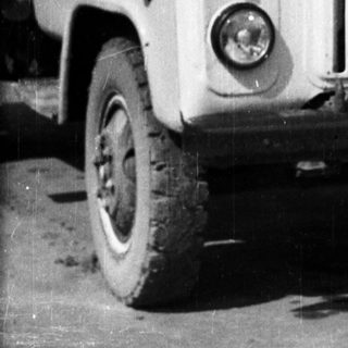 Man sits on a vintage truck in front of a house.