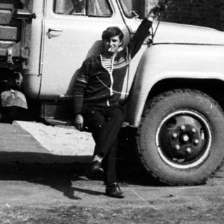 Man stands next to a truck in front of a building.