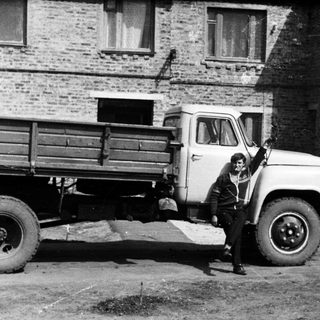 Man stands next to a truck in front of a building.
