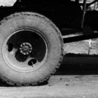 Man stands next to a truck in front of a building.