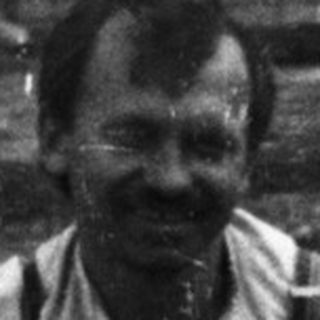 Man sits on a crate near a building site.