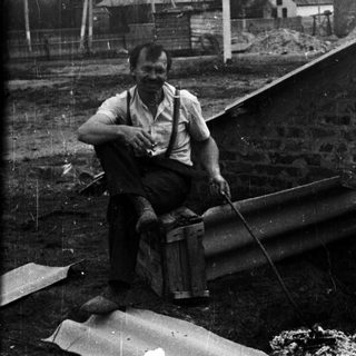 Man sits on a crate near a building site.