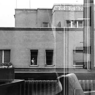 Black and white image of a building seen through a window.
