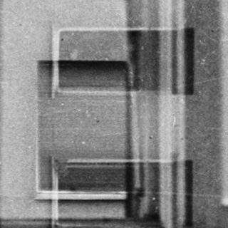 Black and white image of a building seen through a window.