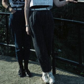 Two young women stand on a ledge overlooking greenery.