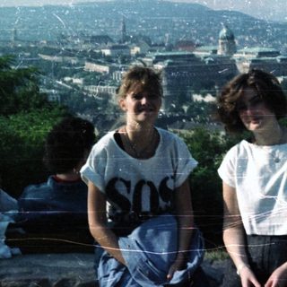 Two people sitting overlooking a city landscape and river.