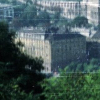 Here's a brief summary of the image: Scenic view of Budapest cityscape, river, and distant hills.
