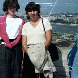 People overlooking Budapest from a rooftop, likely tourists.