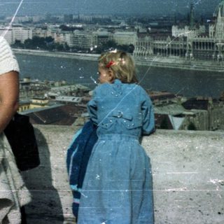 People overlooking Budapest from a rooftop, likely tourists.