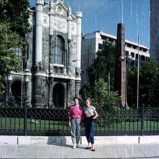 Two people stand in front of a stately building.