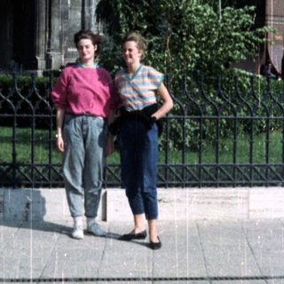 Two people stand in front of a stately building.