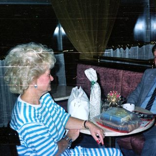 People seated in a room with gifts on a table.