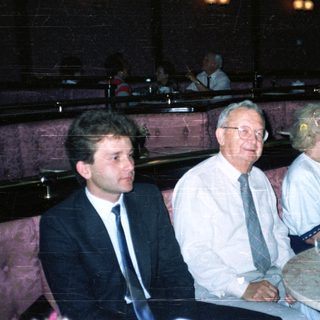 Here's a brief summary of the image: People seated in a restaurant booth, appearing to be dining.