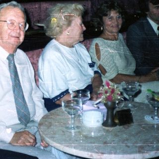 Here's a brief summary of the image: People seated in a restaurant booth, appearing to be dining.