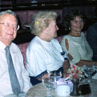 Here's a brief summary of the image: People seated in a restaurant booth, appearing to be dining.