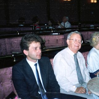 Here's a brief summary of the image: People seated in a restaurant booth, appearing to be dining.