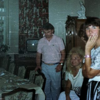 People in a dining room with a television.