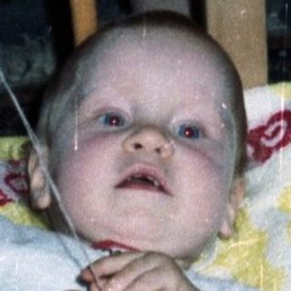 Baby in a crib with toys, looking upwards.
