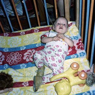 Baby in a crib with toys, looking upwards.