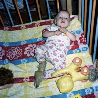 Baby in a crib with toys, looking upwards.
