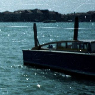 Boat on water with Venice and islands in distance.