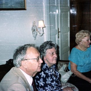 Three people seated in a room with antique furniture.