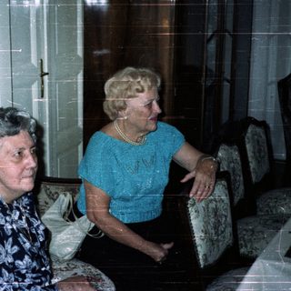 Three people seated in a room with antique furniture.