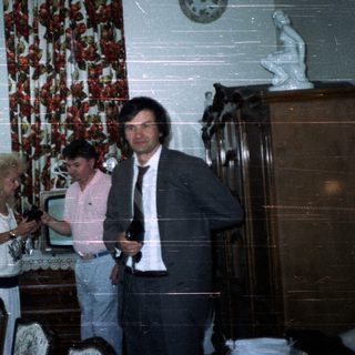 Three people in a dining room with a decorated table.